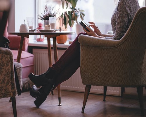 A laptop on a cozy wooden cafe table next to a window with warm morning light